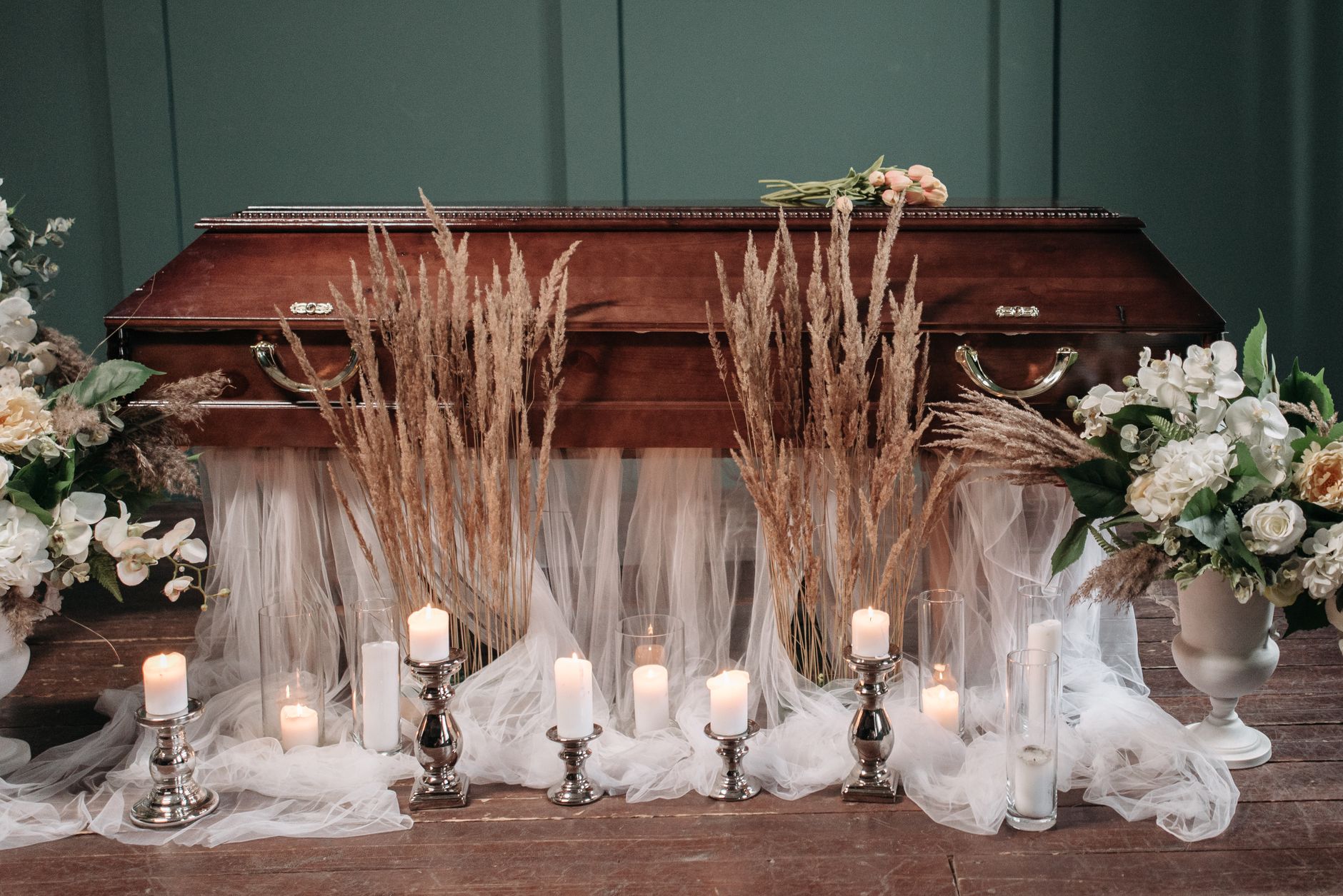 A dignified casket arrangement with white flowers and candleholders